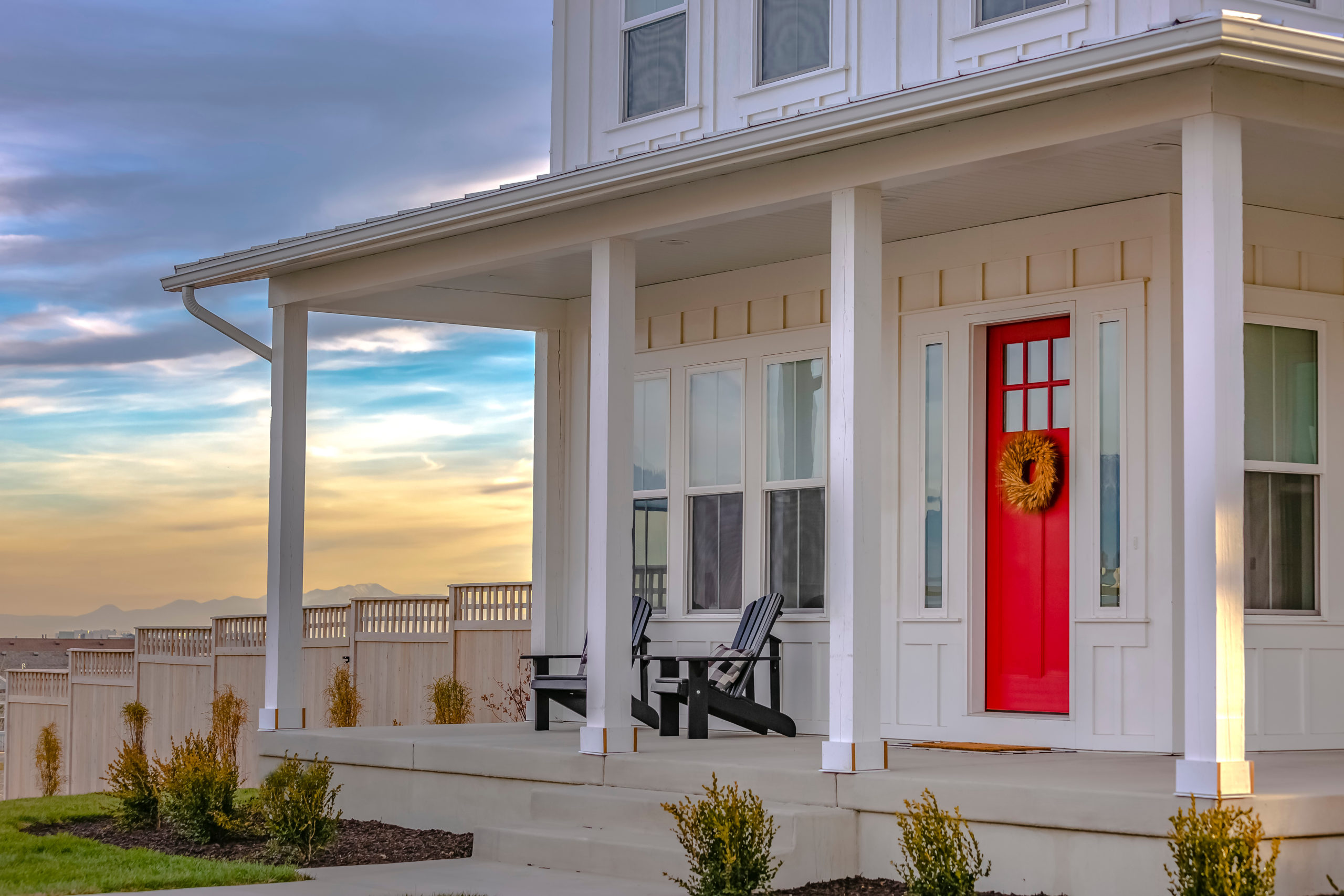 White house with 4 white pillars and a red door in the evening with a sunset